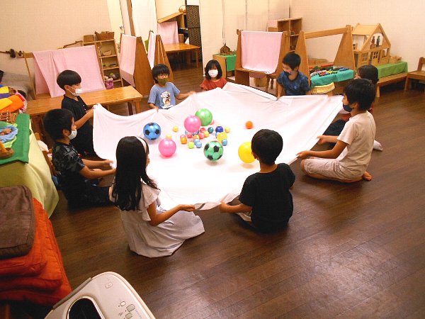 小学生クラスの、シートと多数のボールを使ったチームワークや動きを育むゲーム遊び