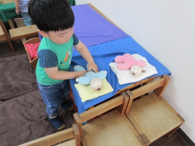 幼児クラスでのごっこ遊び、布製の人形に枕をあてて寝かしつける様子"